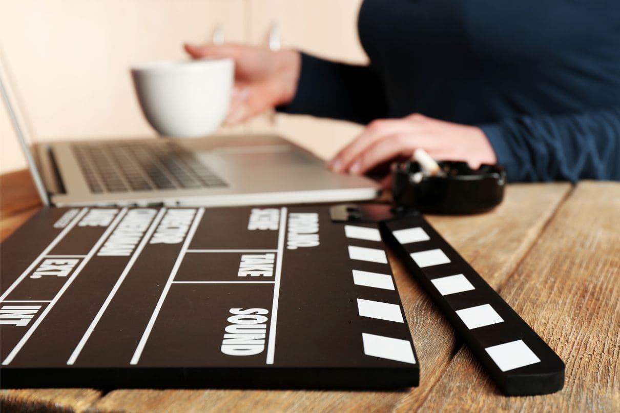 A person at a table with a laptop and a clapper board, prepared for productive work.